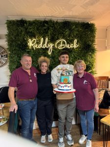 Bake off Champion 2023 Matty shows off his cake with Ruddy Duck staff Nigel, Jo and Annette